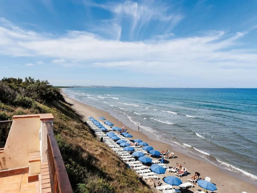 Spiaggia sabbiosa con lettini e ombrelloni blu vista dall'alto sul mare