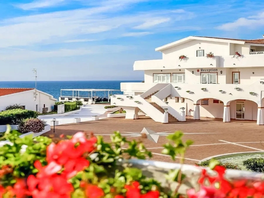 Edificio bianco della reception con scalinata e fiori rossi vista mare