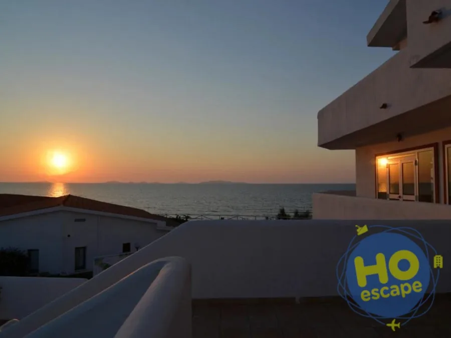 Vista del tramonto sul mare da una terrazza del resort con edifici bianchi