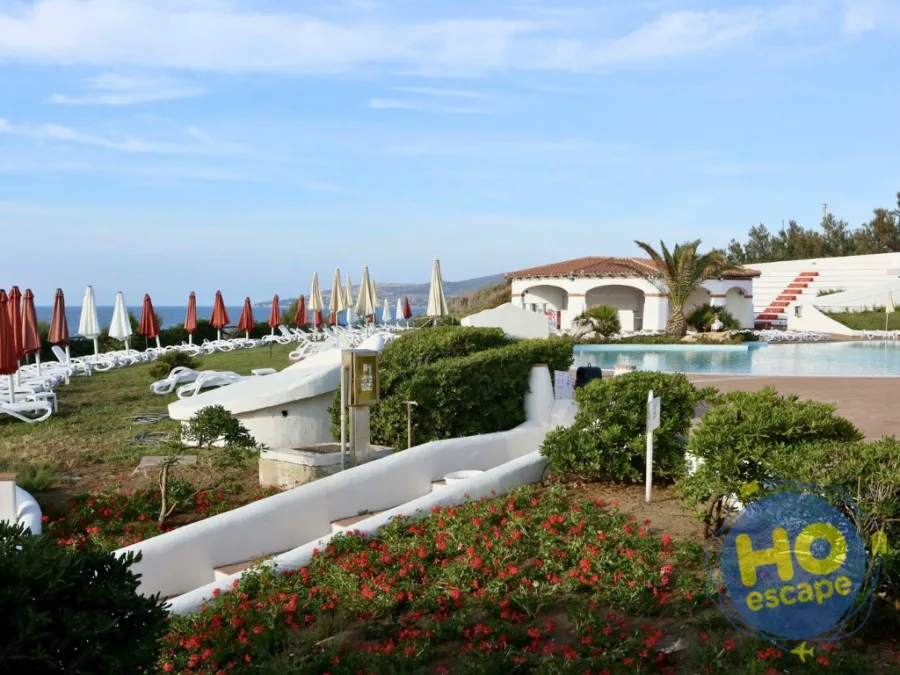 Giardino fiorito con piscina, lettini e ombrelloni vista mare