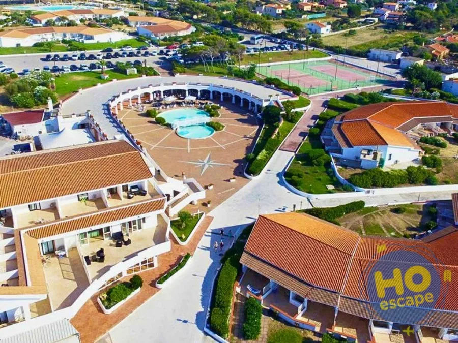 Vista aerea del resort con piscina centrale, campi da tennis e edifici