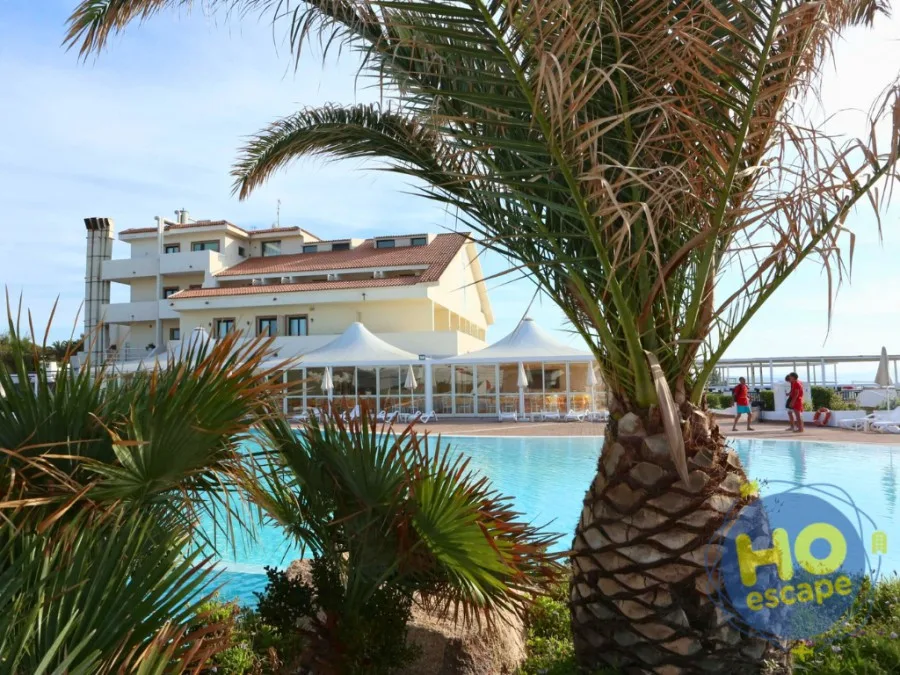 Piscina del resort con palme in primo piano e edificio principale sullo sfondo