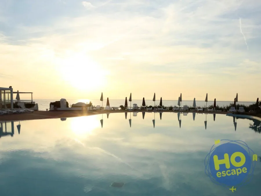 Piscina a sfioro al tramonto con vista sul mare e ombrelloni chiusi