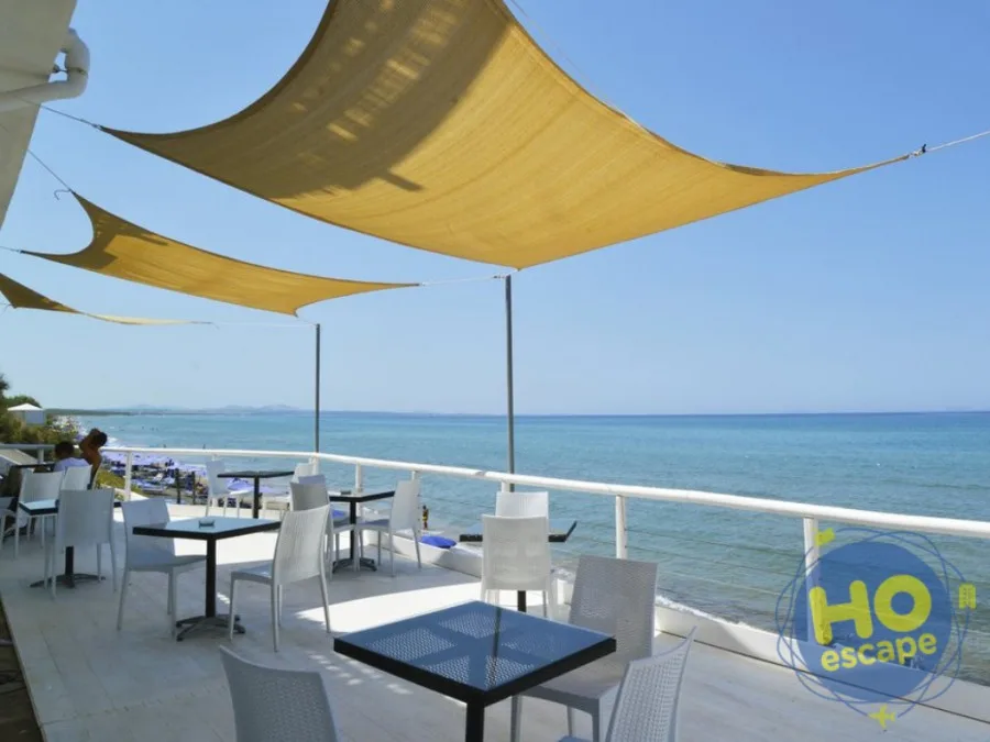 Terrazza ristorante con tavoli e vele parasole gialle vista mare