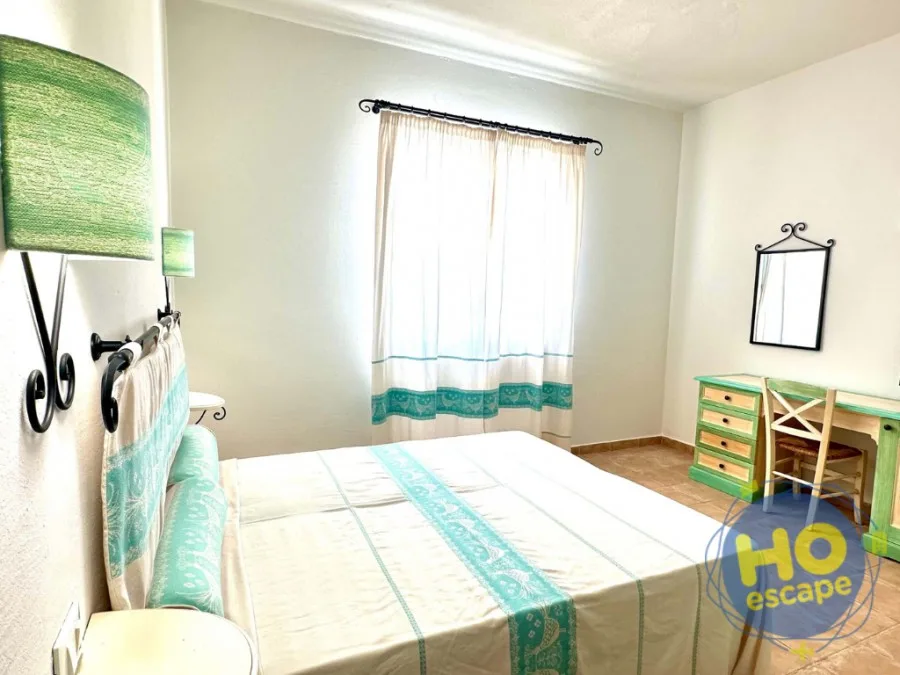 Camera con letto matrimoniale, scrivania verde e tende decorate