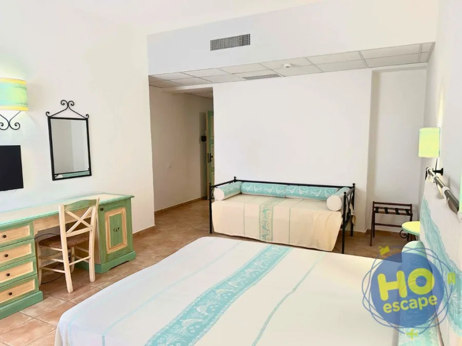 Camera spaziosa con letto, divano e scrivania in stile mediterraneo
