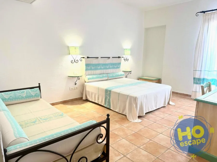 Camera con letto matrimoniale e letto singolo, arredi in ferro battuto e dettagli color turchese
