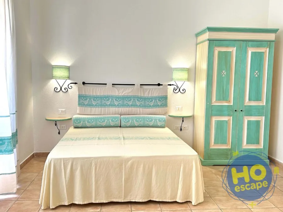 Camera matrimoniale con armadio in legno verde acqua e testiera decorata