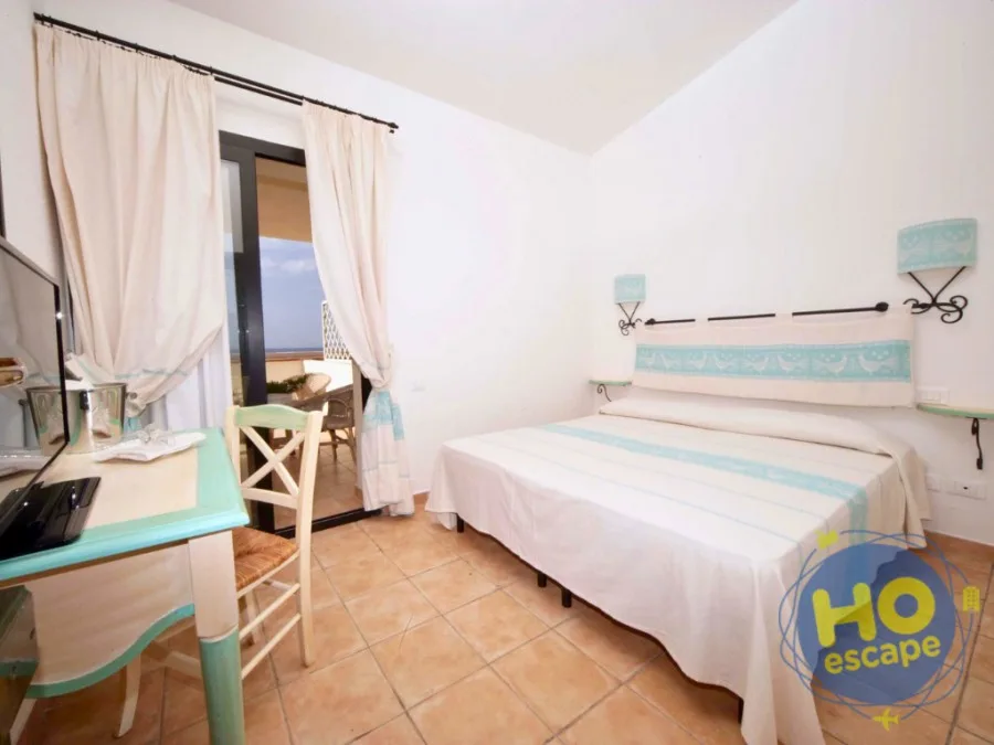 Camera con letto, scrivania e porta finestra con vista mare