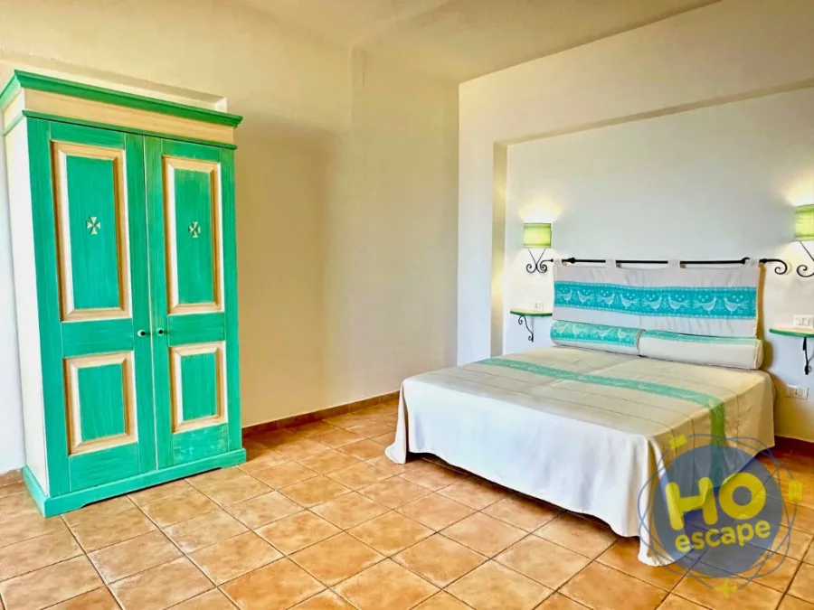 Camera spaziosa con armadio verde acqua e letto con testiera decorata
