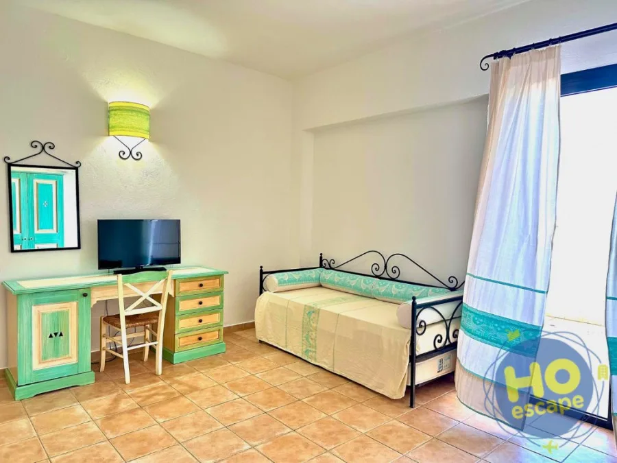 Camera con divano letto, scrivania, TV e specchio decorativo