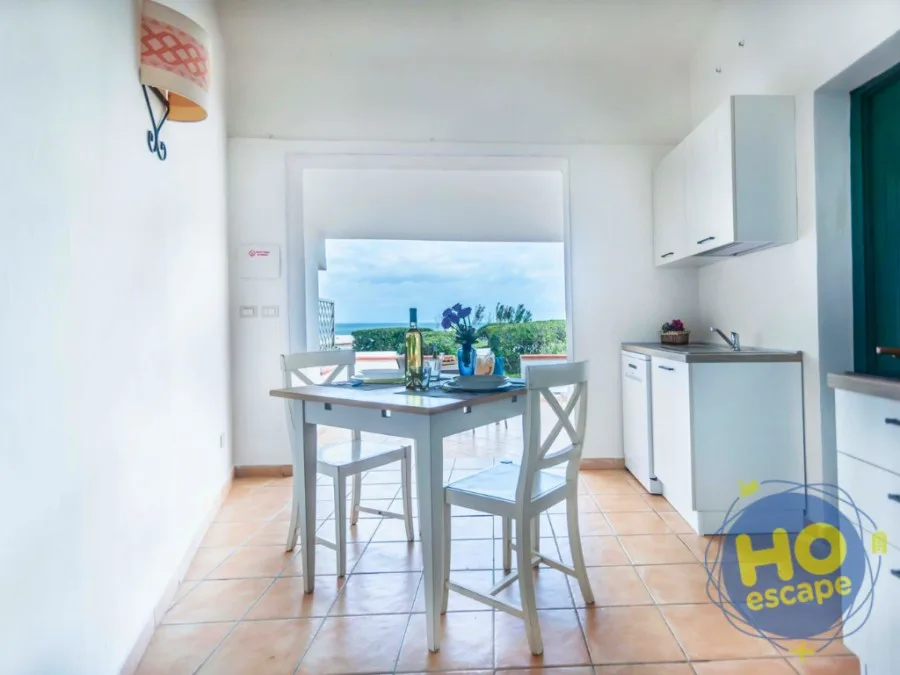 Angolo cottura con tavolo apparecchiato e finestra con vista mare