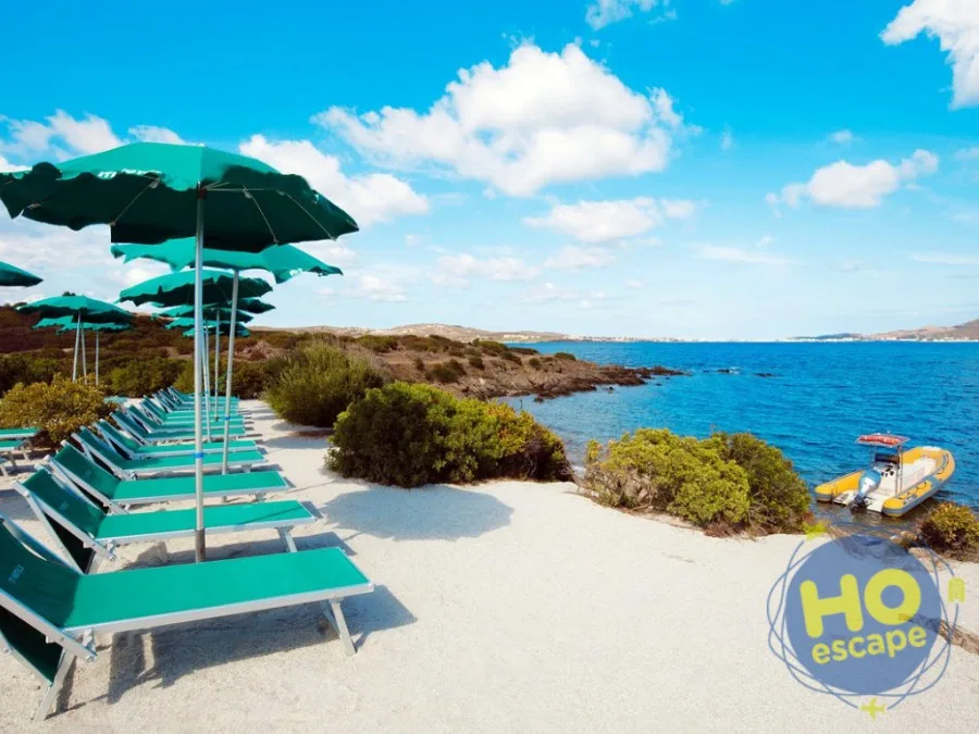 Lettini e ombrelloni verdi su spiaggia di sabbia bianca con vista sul mare e gommone ormeggiato