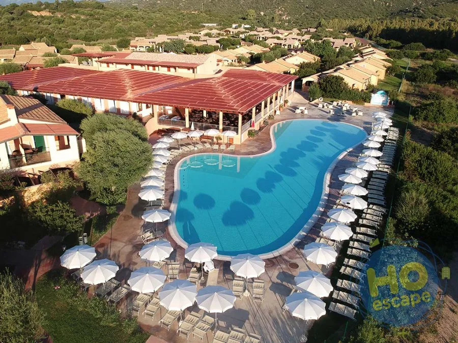 Veduta aerea della grande piscina con ombrelloni bianchi e lettini