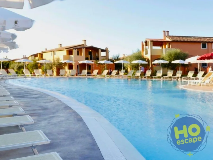 Piscina con lettini e ombrelloni circondata dagli edifici del villaggio