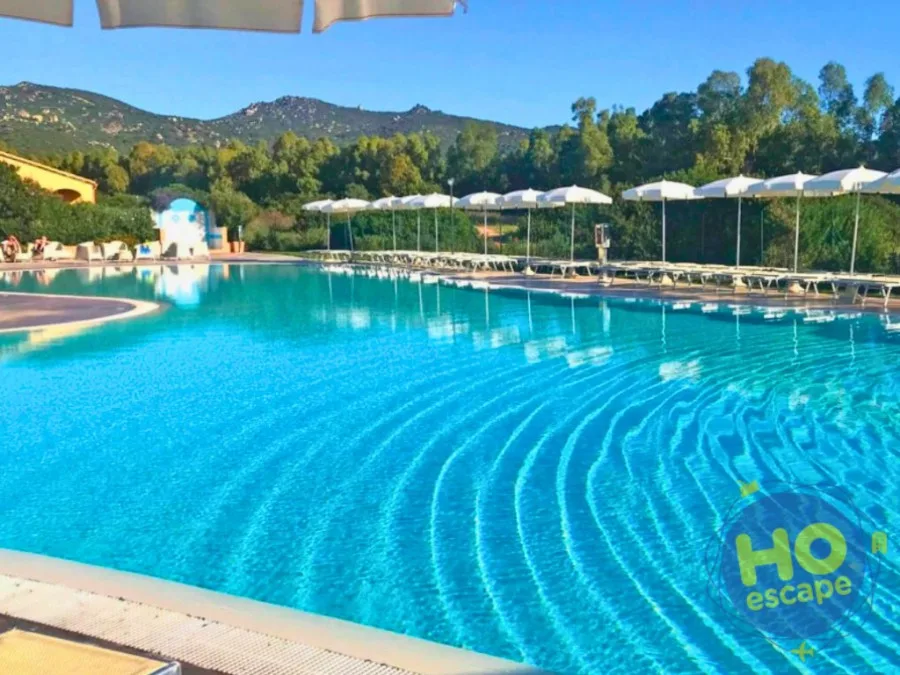 Ampia piscina con acqua azzurra e vegetazione sullo sfondo