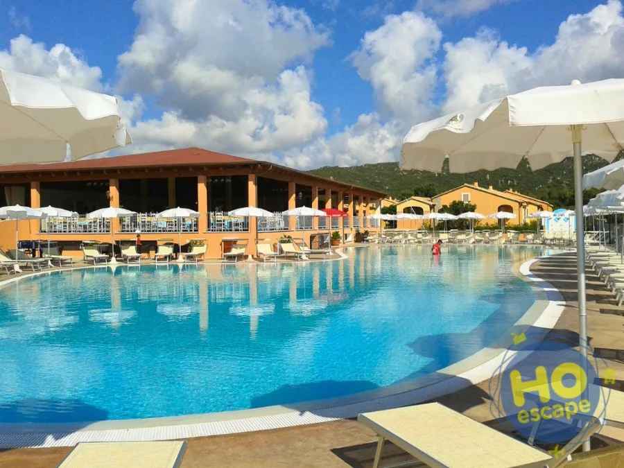 Piscina con lettini, ombrelloni bianchi e cielo nuvoloso