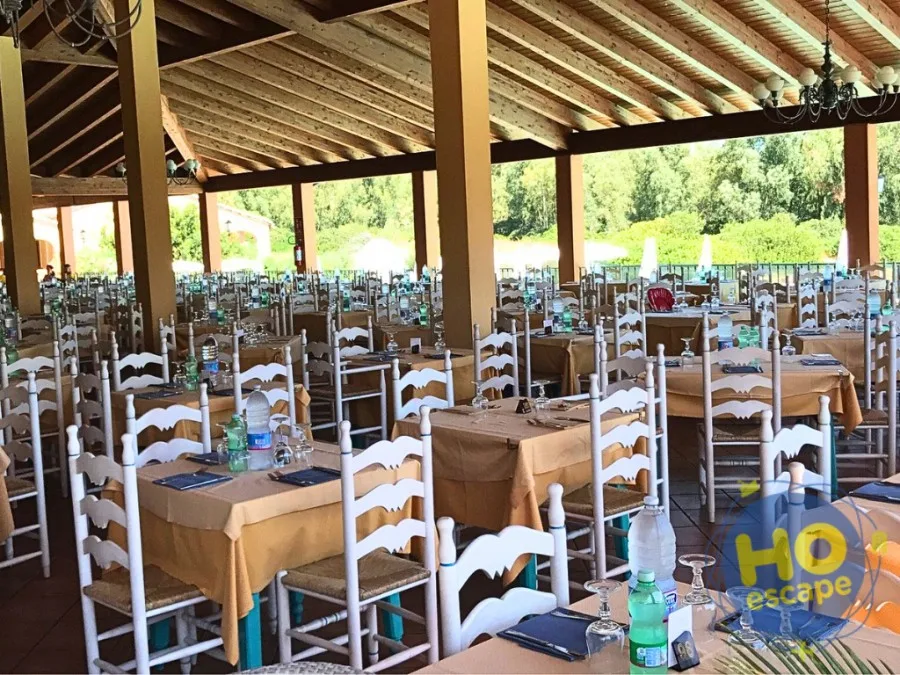 Sala ristorante all'aperto con tavoli apparecchiati e tetto in legno