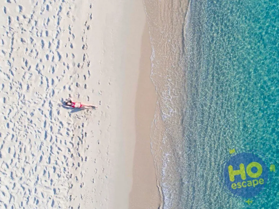 Veduta aerea di persona distesa sulla spiaggia di sabbia bianca