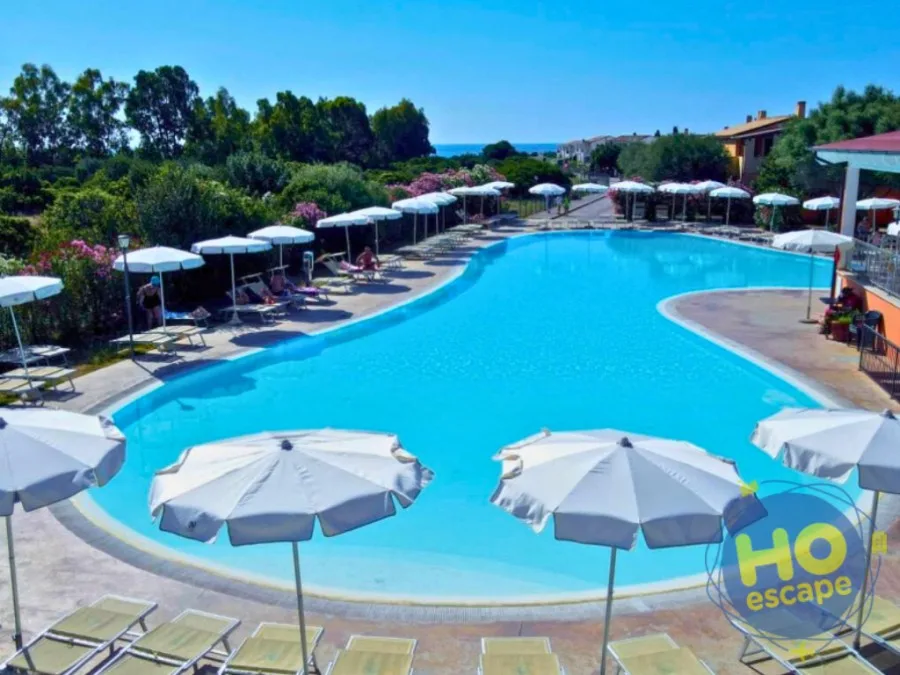 Piscina del resort con ombrelloni, lettini e vista sul mare