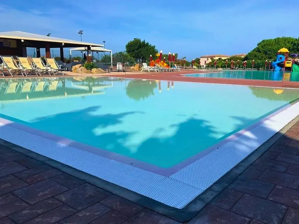 Piscina con acqua cristallina, lettini e area giochi per bambini