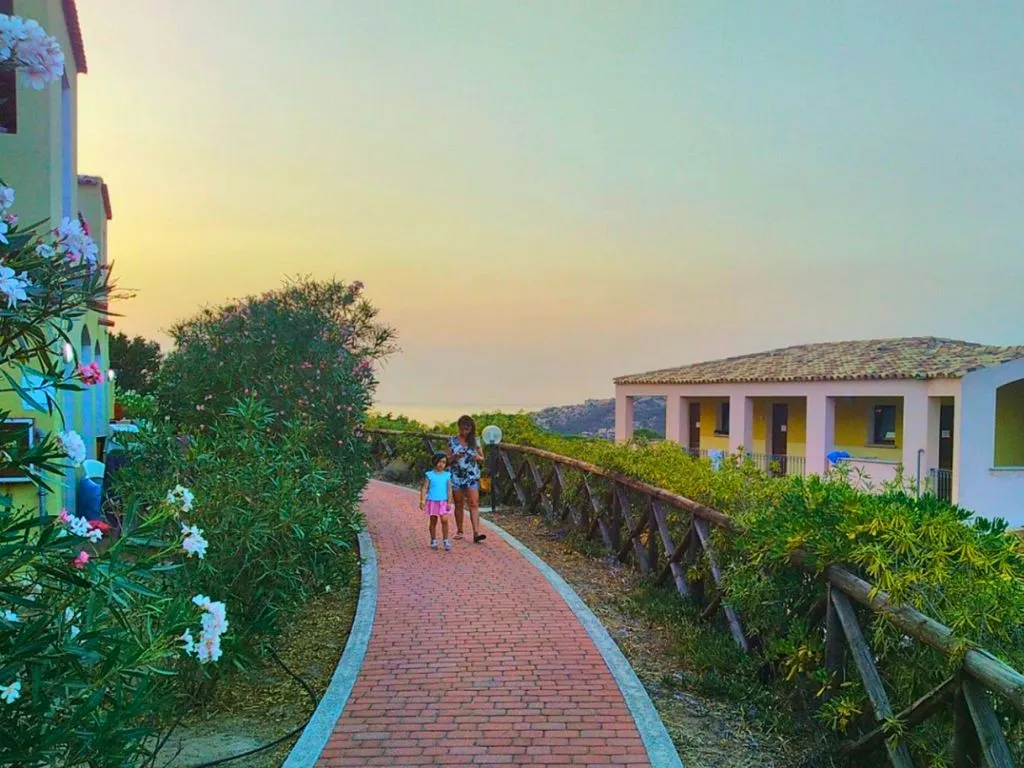 Vialetto in mattoni del villaggio al tramonto con fiori e vista mare