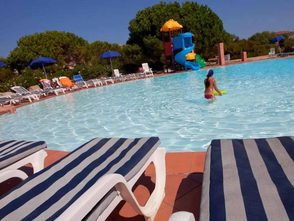 Bordo piscina con lettini a righe e scivolo colorato per bambini
