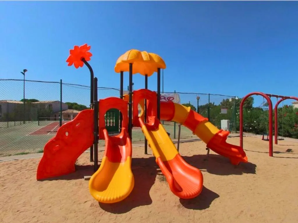Parco giochi colorato con scivoli su sabbia e campi sportivi