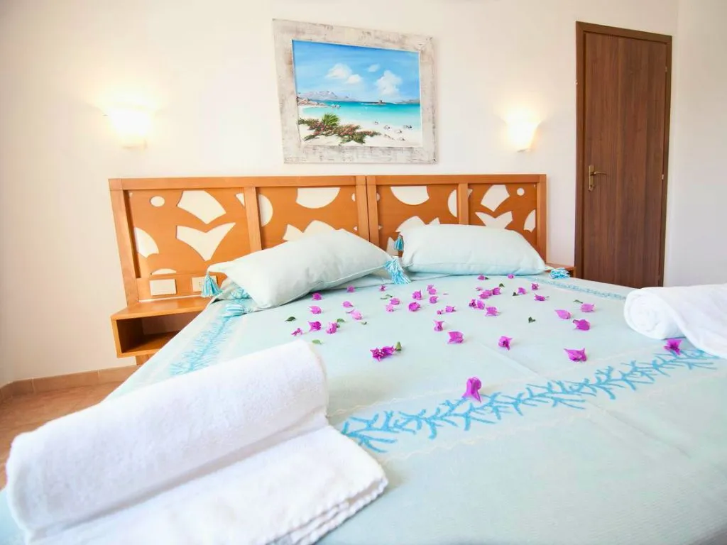 Camera matrimoniale con letto decorato di fiori e quadro marino