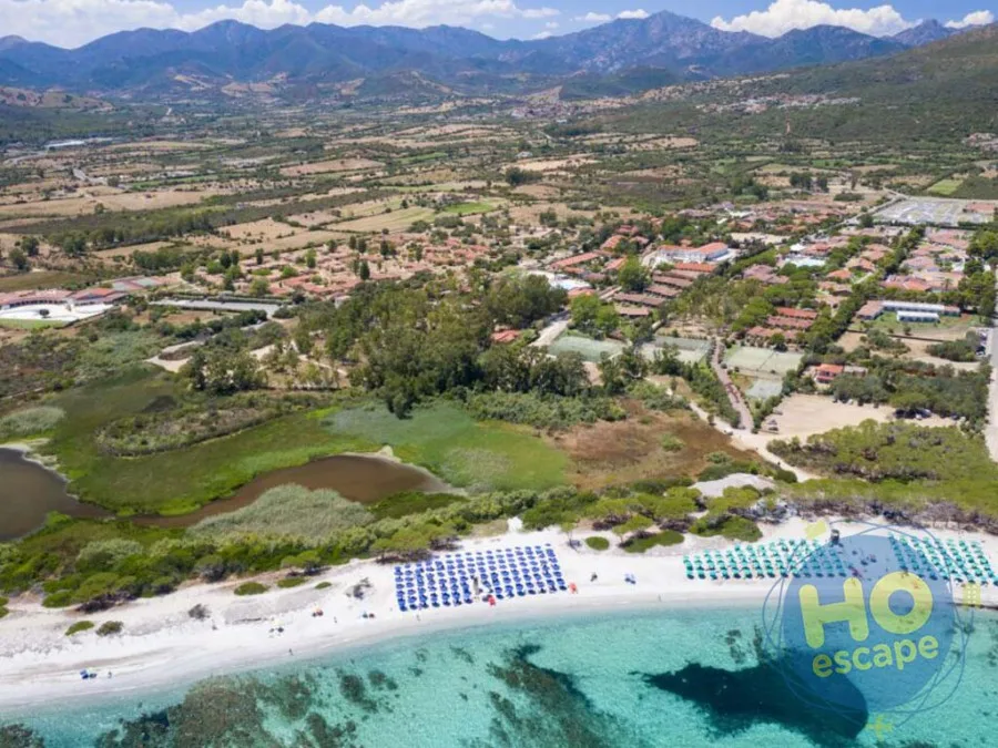 Vista aerea del territorio con montagne, campagna, resort e spiaggia con ombrelloni