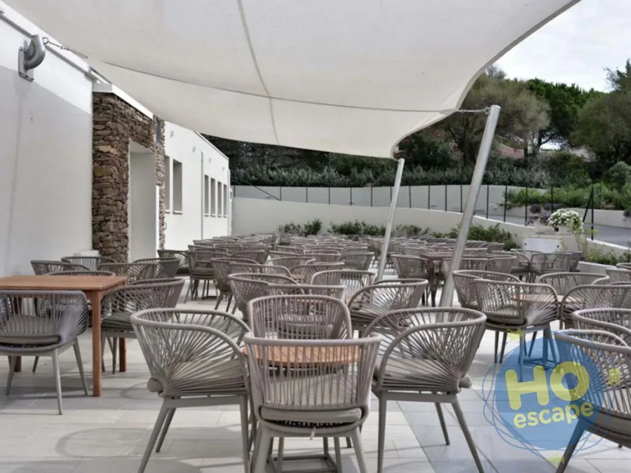 Area lounge esterna con poltroncine in corda grigia sotto vele ombreggianti bianche