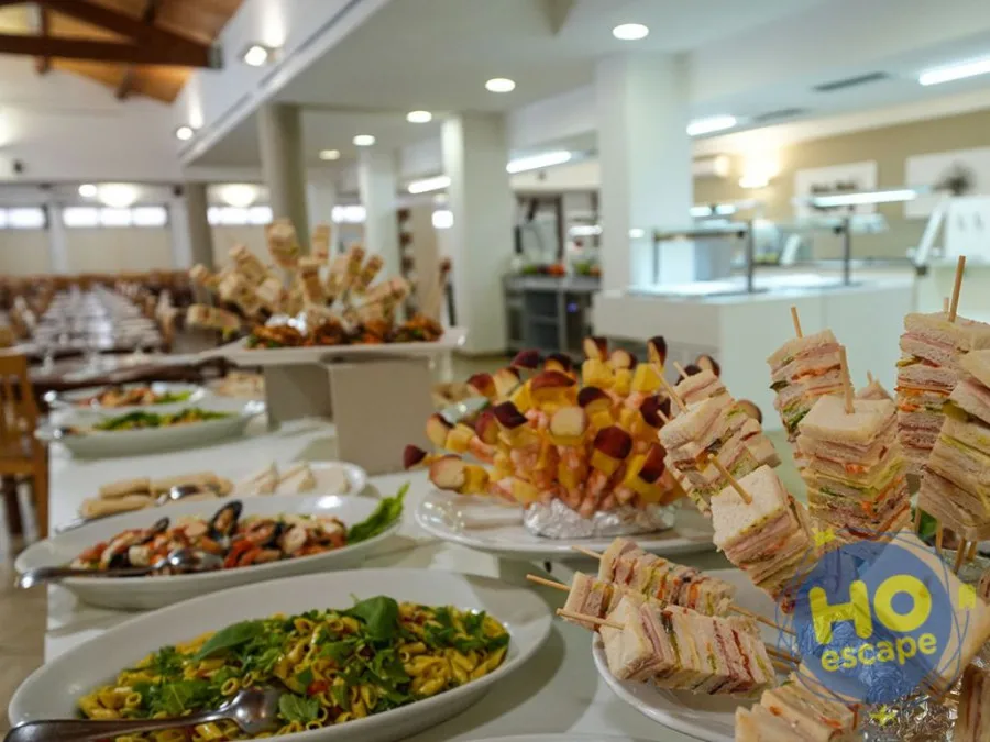 Buffet con tramezzini, spiedini di frutta e piatti di pasta nella sala ristorante