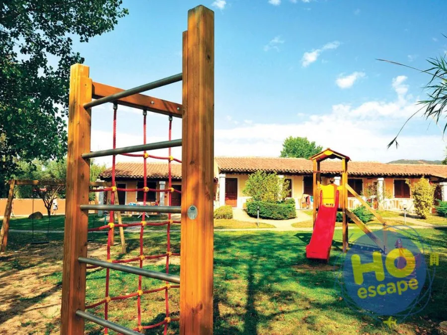 Area giochi per bambini con scivolo e struttura da arrampicata in legno nel giardino dell'hotel