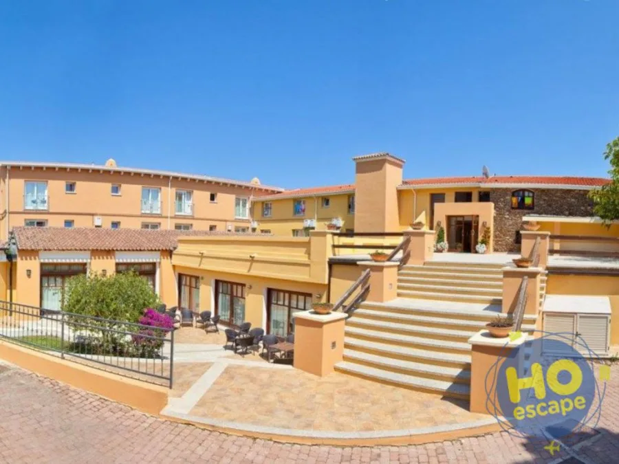 Esterno dell'hotel in stile mediterraneo con facciata color ocra, scalinata d'ingresso e terrazza arredata