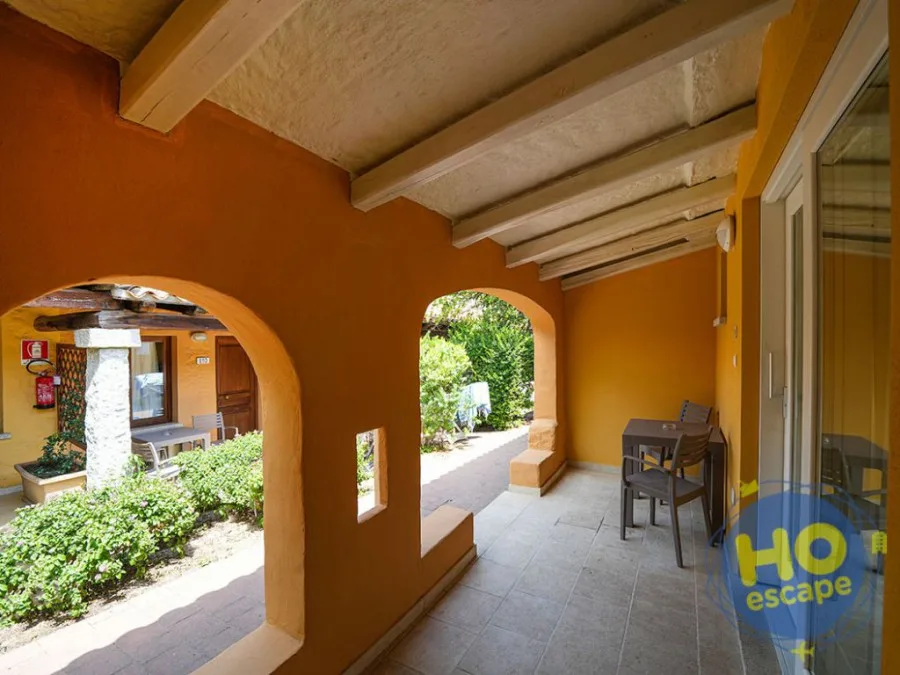 Veranda esterna con archi color ocra, tavolo e sedie affacciata sul giardino