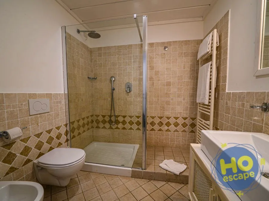 Bagno con doccia in muratura, WC, bidet e piastrelle beige decorate