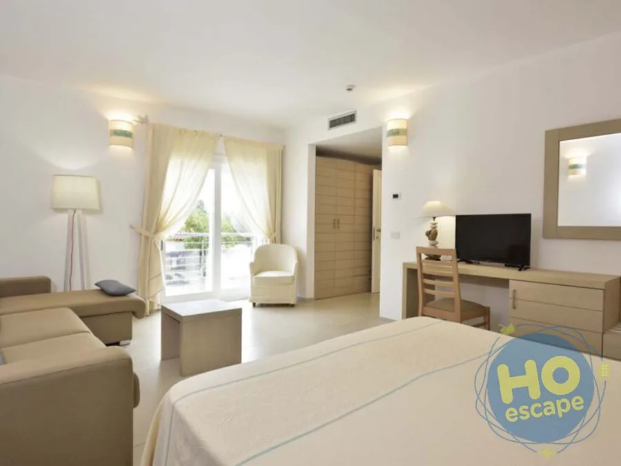 Ampia camera con zona soggiorno, divano, scrivania e accesso al balcone