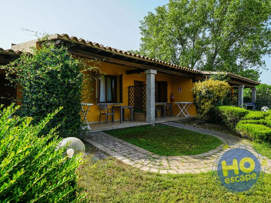 Villetta gialla con veranda, giardino verde e vialetto in pietra