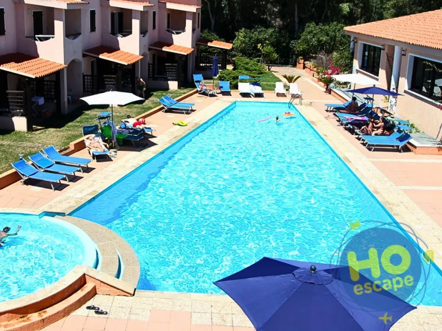 Piscina rettangolare con vasca idromassaggio, ombrelloni e lettini blu