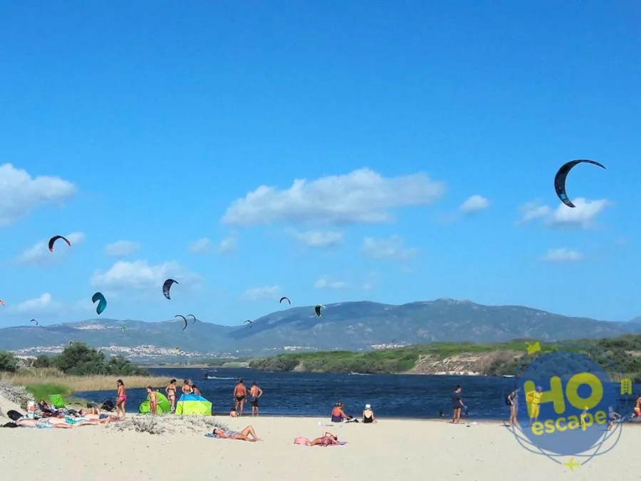 Spiaggia con kitesurf in volo, mare e colline sullo sfondo