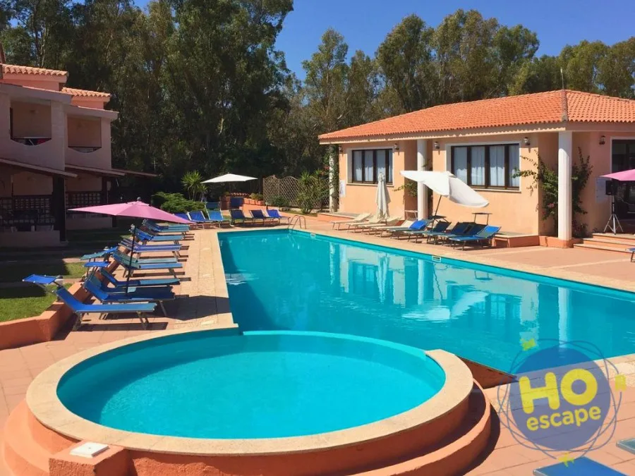 Piscina con vasca idromassaggio, ombrelloni rosa e lettini blu