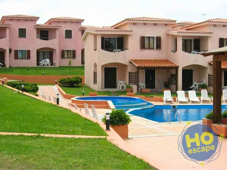 Villette rosa del residence con prato verde e piccola piscina