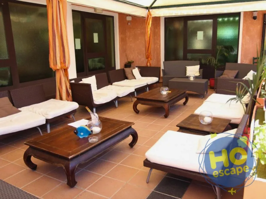 Lounge esterno con divani in rattan marrone e cuscini bianchi