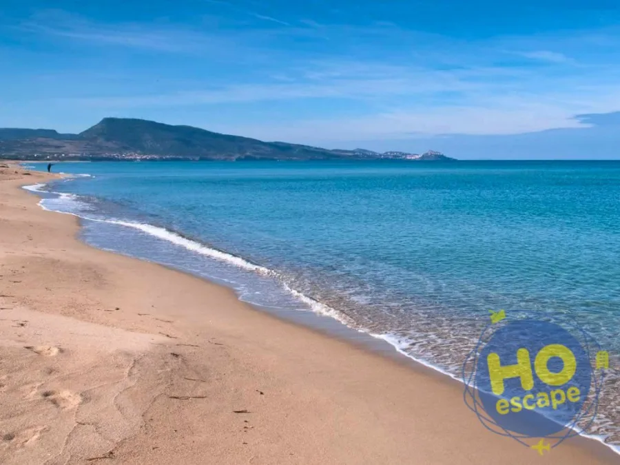 Spiaggia sabbiosa con mare azzurro e promontorio all'orizzonte