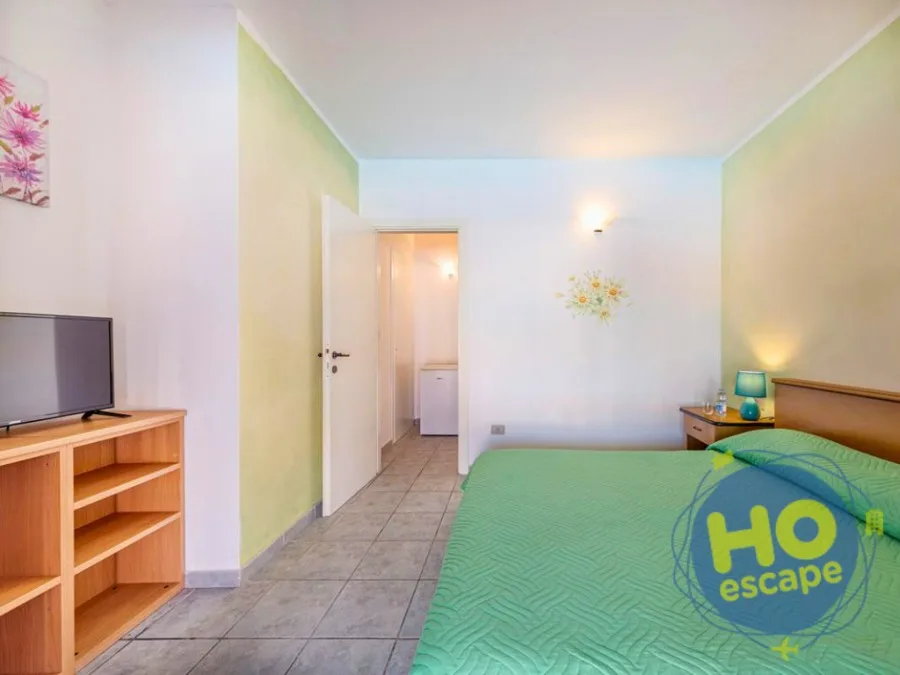 Camera da letto con pareti gialle, TV e ingresso al bagno