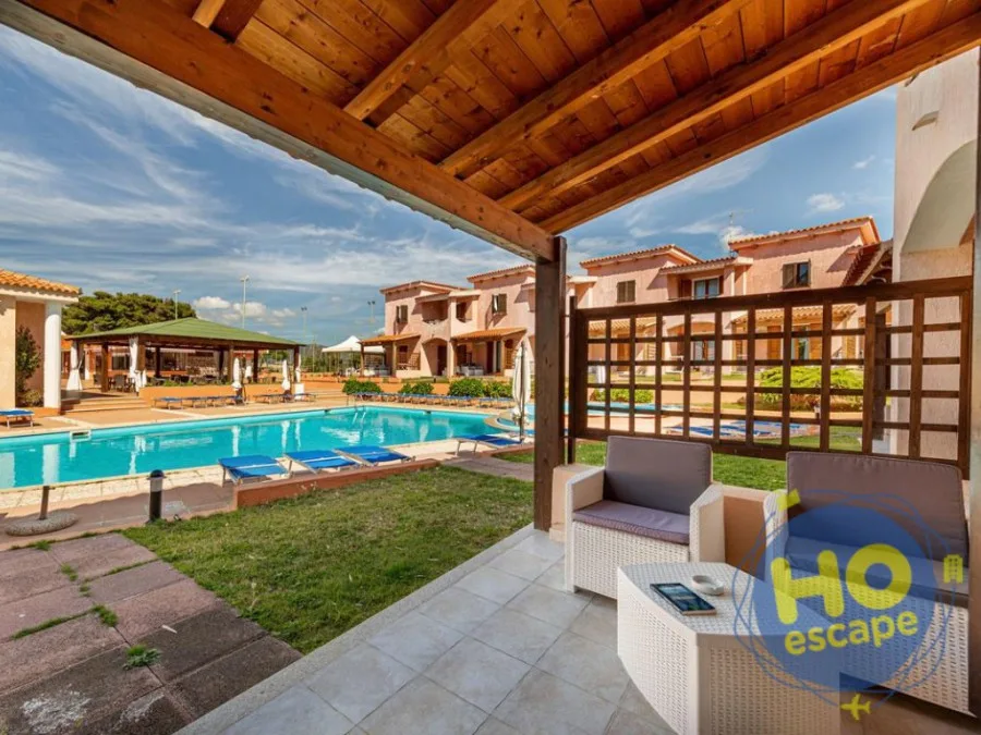 Veranda con divano in rattan vista piscina e villette del residence