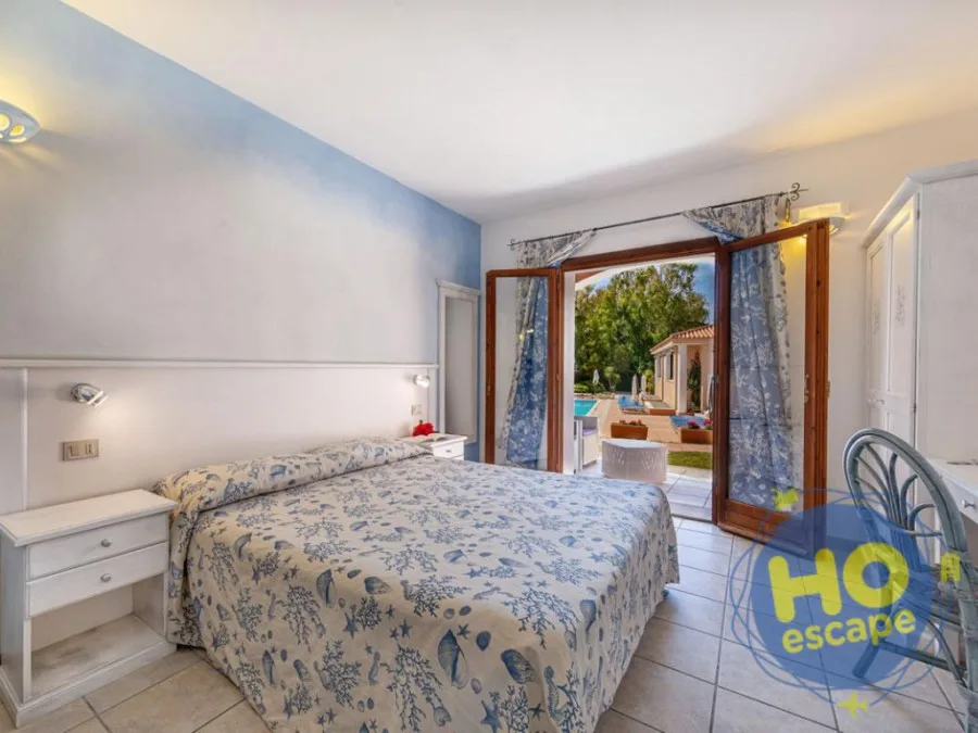 Camera con letto matrimoniale azzurro e uscita sul patio vista piscina