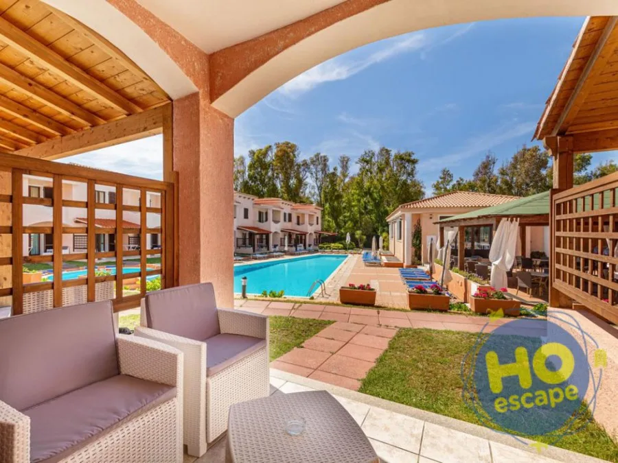 Veranda con poltrone in rattan e vista sulla piscina del residence