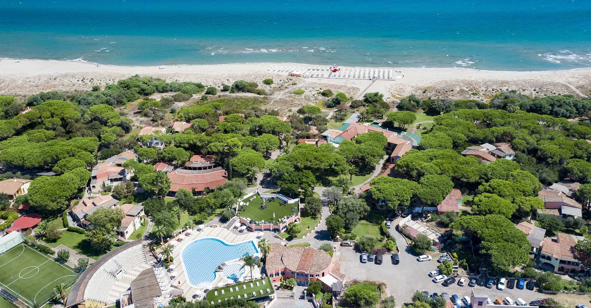 Vista aerea del villaggio turistico tra i pini con piscina e spiaggia sul mare