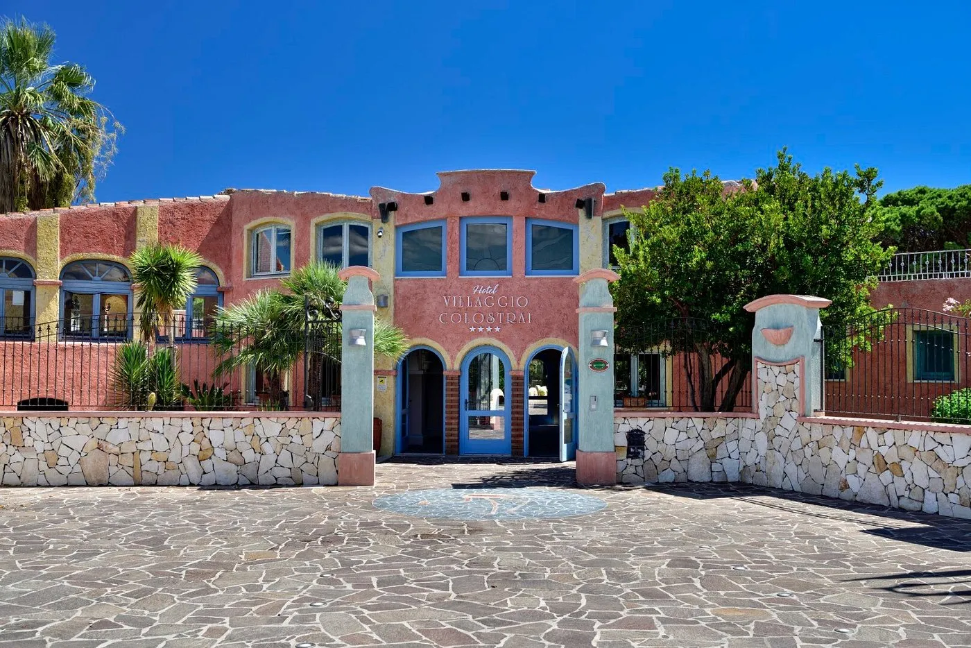 Ingresso dell'Hotel Villaggio Colostrai con facciata color terracotta e archi